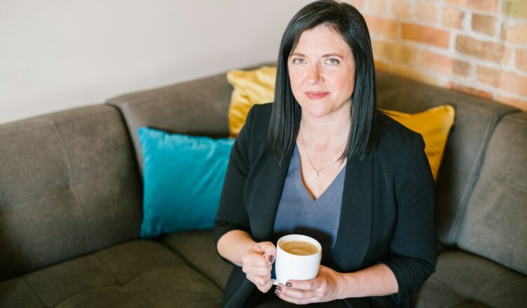 woman holding cup of coffee sitting on sofa